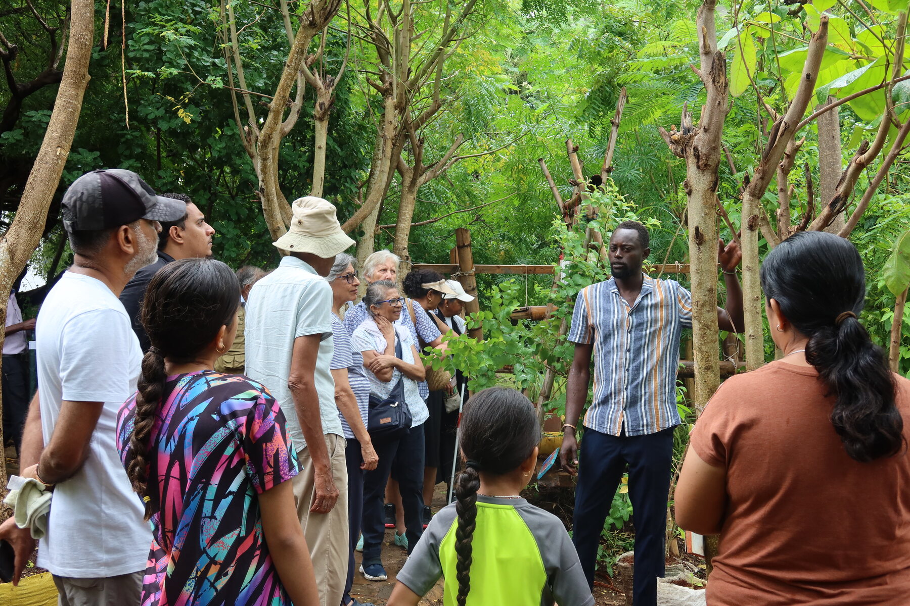 Teddy Katono guiding a group through a green kitchen garden.